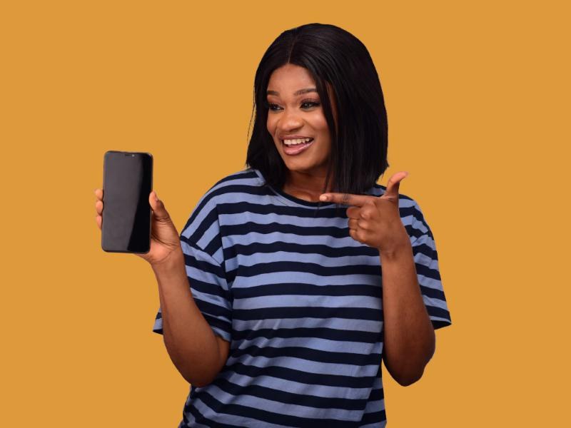 A smiling student pointing at her phone