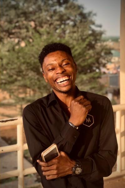 A young man laughing outdoors with his phone