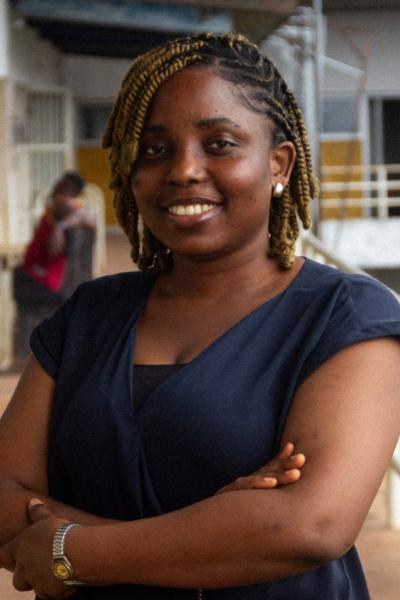 A smiling student with braids outside a faculty building